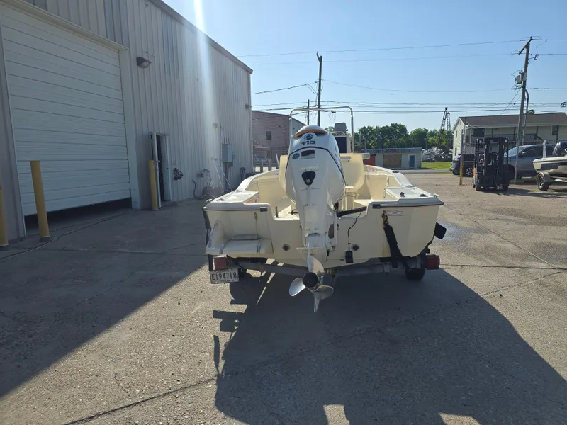 Slide: The Image of 1993 Scout 172 Sportfish boat with outboard motor, parked outdoors in a sunny industrial area. - 5