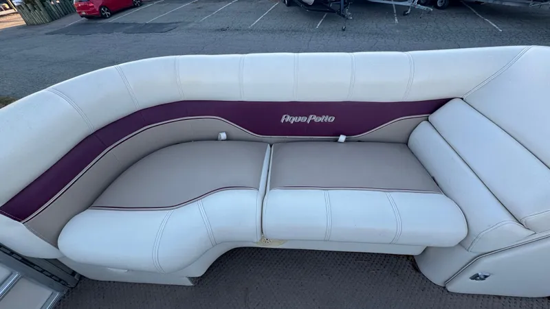 Slide: The Image of 2005 AquaPatio Cruise boat seating with white and maroon upholstery in a parking area. - 3