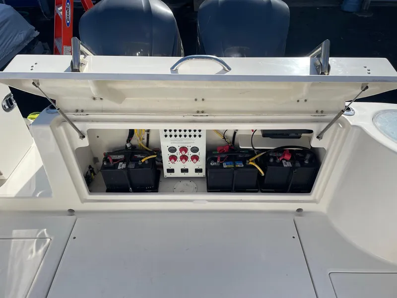 Slide: The Image of 2009 Robalo R305 Walkaround boat battery compartment with open hatch, showing multiple batteries and wiring. - 10