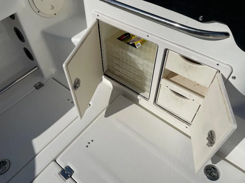 Slide: The Image of 2009 Robalo R305 Walkaround boat storage compartment with open doors and drawers. - 13