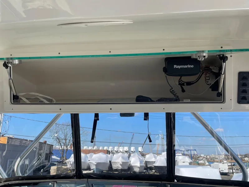 Slide: The Image of 2009 Robalo R305 Walkaround boat interior with Raymarine electronics and open storage compartment. - 25