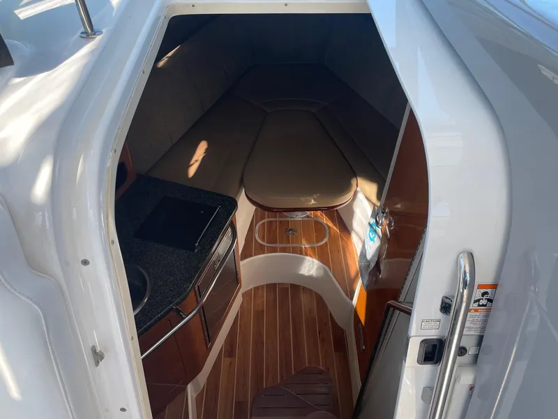 Slide: The Image of 2009 Robalo R305 Walkaround cabin interior with wood flooring and compact kitchenette. - 28