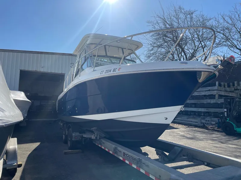 Slide: The Image of 2009 Robalo R305 Walkaround boat on trailer, parked outside a warehouse. - 3