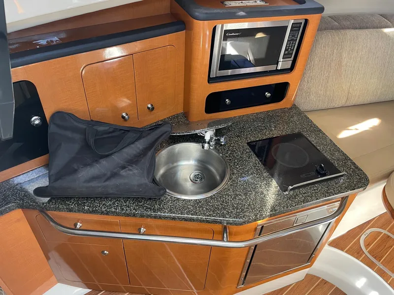 Slide: The Image of 2009 Robalo R305 Walkaround boat kitchen with sink, microwave, and stove. - 30