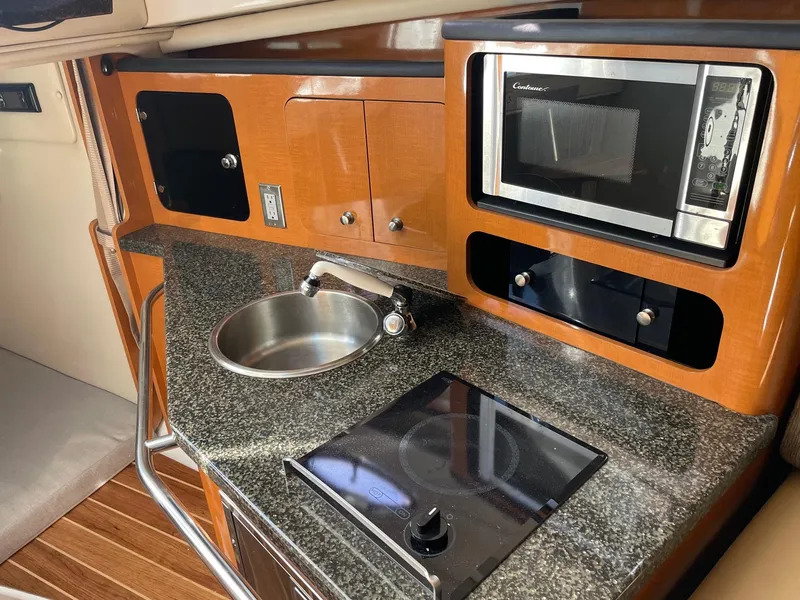 Slide: The Image of 2009 Robalo R305 Walkaround boat kitchen with sink, microwave, and stove. - 31