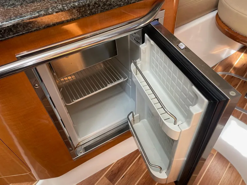 Slide: The Image of 2009 Robalo R305 Walkaround boat interior with open mini fridge, wooden flooring. - 35