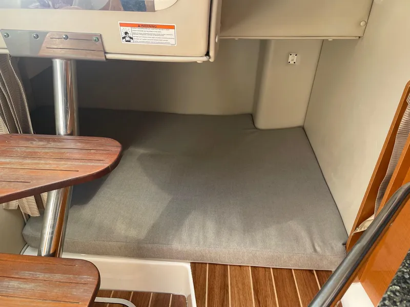 Slide: The Image of 2009 Robalo R305 Walkaround cabin interior with wooden table and cushioned seating area. - 39