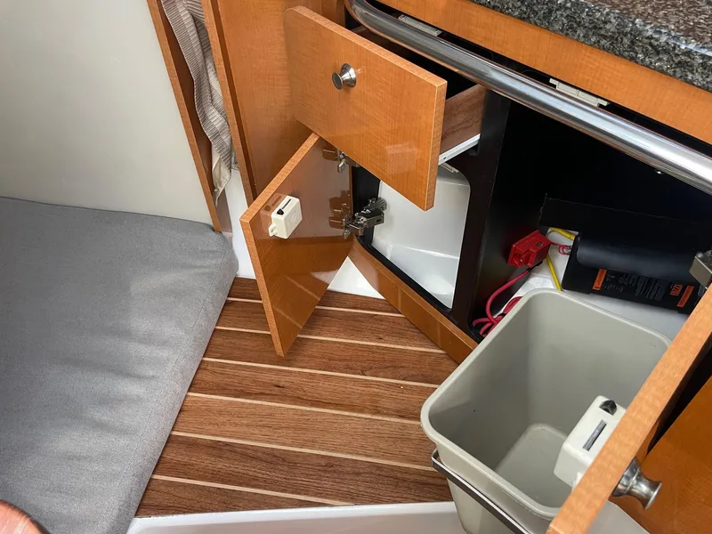Slide: The Image of 2009 Robalo R305 Walkaround interior with open cabinet, wooden flooring, and trash bin. - 41