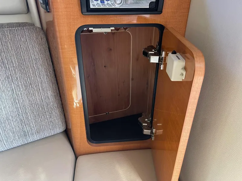 Slide: The Image of Open cabinet in 2009 Robalo R305 Walkaround boat interior, showing wood finish and seating. - 44