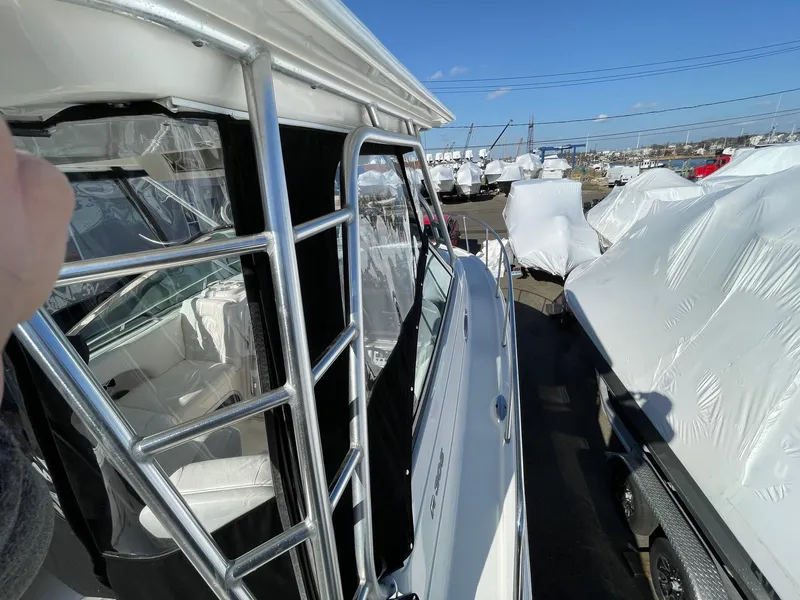 Slide: The Image of 2009 Robalo R305 Walkaround boat, docked, with protective covers, under clear blue sky. - 46