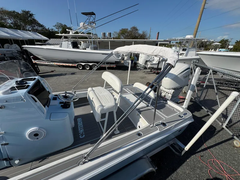 Slide: The Image of 2024 Contender 26 Bay boat with white seating and console, displayed outdoors. - 11