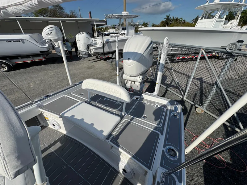 Slide: The Image of 2024 Contender 26 Bay boat deck with motor, parked in a marina under clear skies. - 20