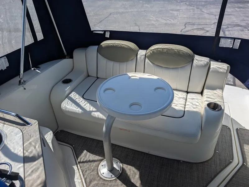 Slide: The Image of 2006 Sea Ray 240 Sundancer interior with cushioned seating and round table. - 11