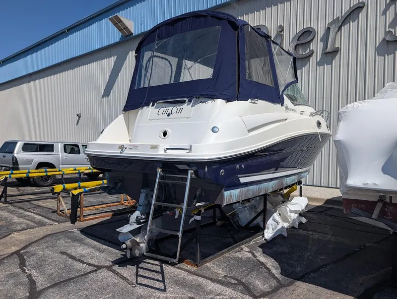 Slide: The Image of 2006 Sea Ray 240 Sundancer boat on dry dock with blue canopy. - 2