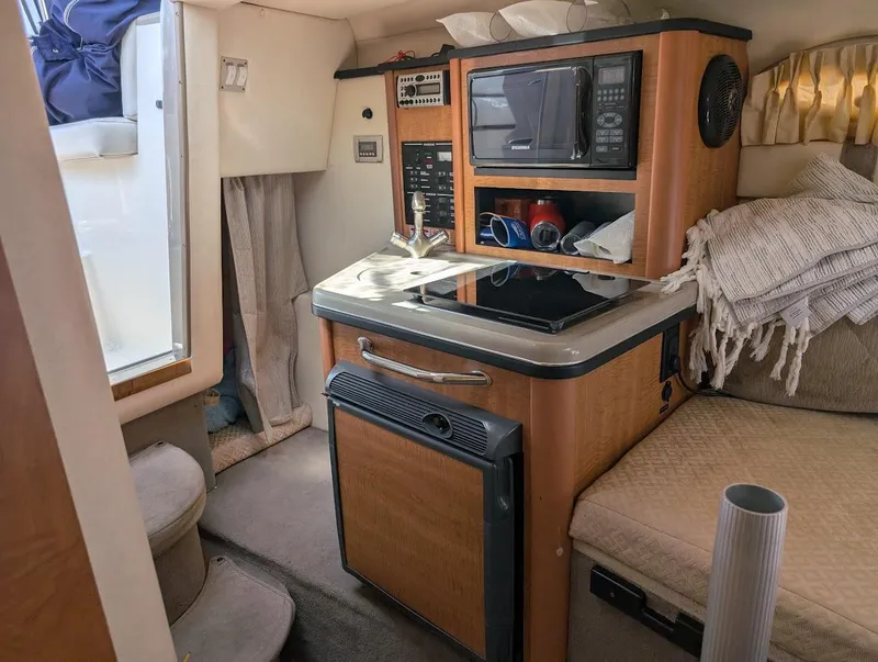 Slide: The Image of 2006 Sea Ray 240 Sundancer cabin with kitchenette, featuring sink, microwave, and compact fridge. - 20