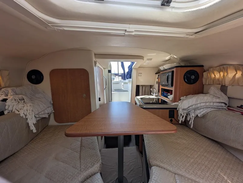 Slide: The Image of Interior of 2006 Sea Ray 240 Sundancer boat with cozy seating and wooden table. - 23