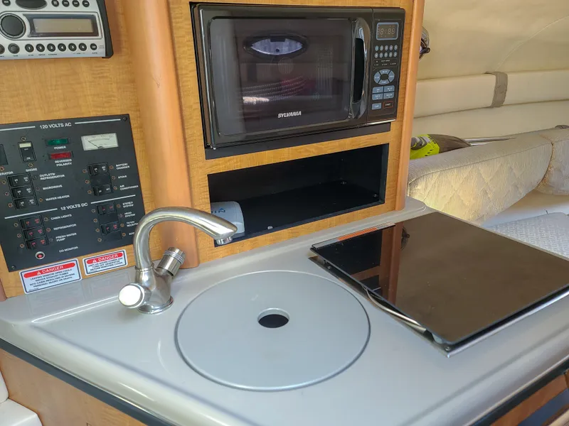 Slide: The Image of 2006 Sea Ray 240 Sundancer interior with kitchenette, featuring sink, microwave, and control panel. - 30