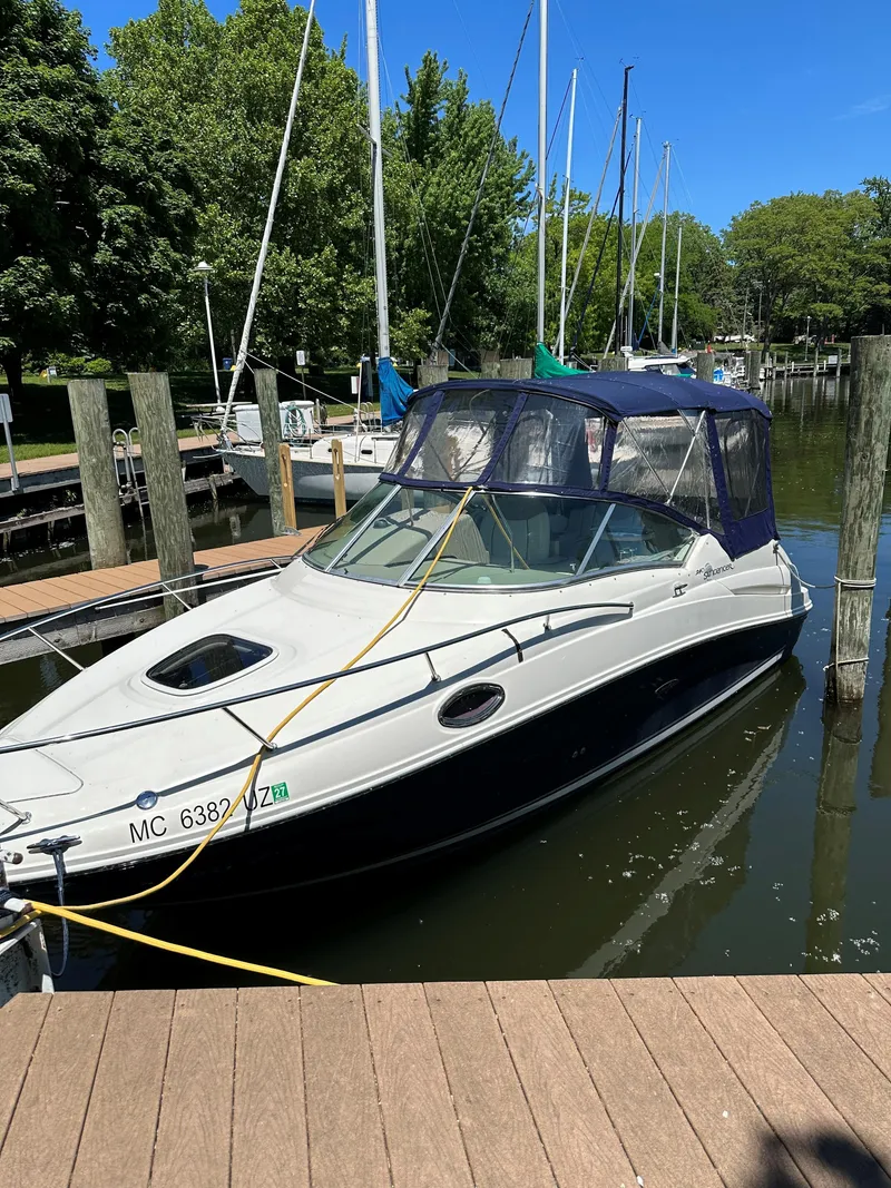 Slide: The Image of 2006 Sea Ray 240 Sundancer docked at a marina, surrounded by trees and clear blue sky. - 5
