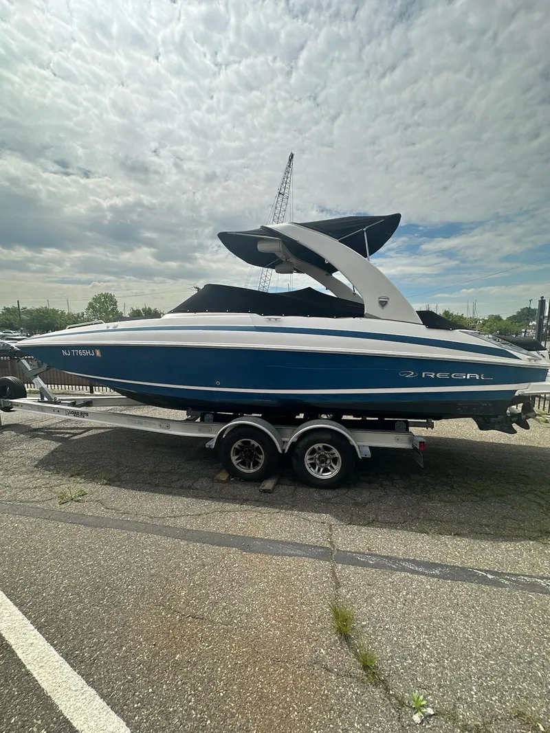 Slide: The Image of 2014 Regal 2700 Bowrider boat on trailer, blue and white design, parked outdoors. - 12