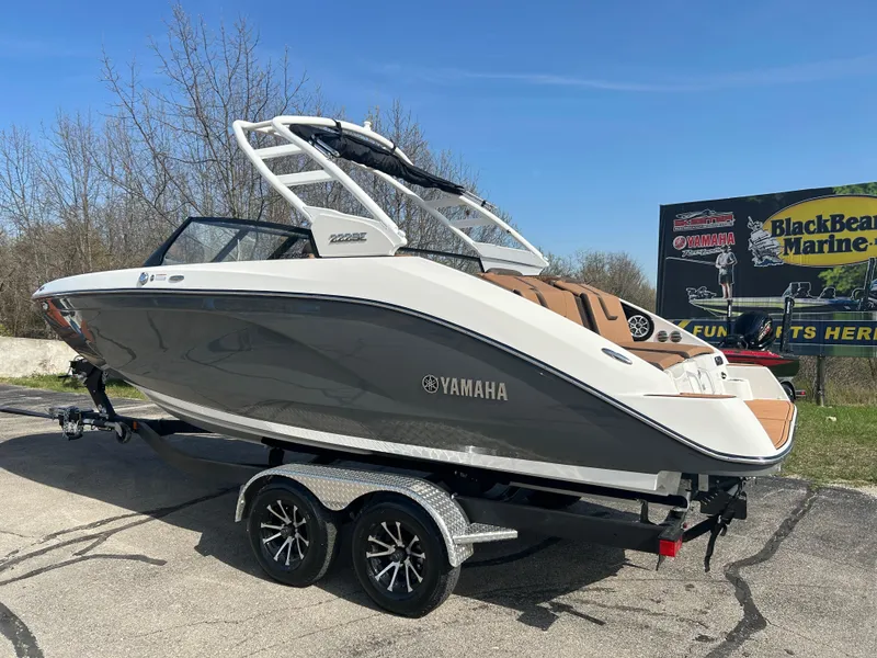 Slide: The Image of 2025 Yamaha Boats 222SE on trailer, sleek design, gray and white exterior, parked outdoors. - 4