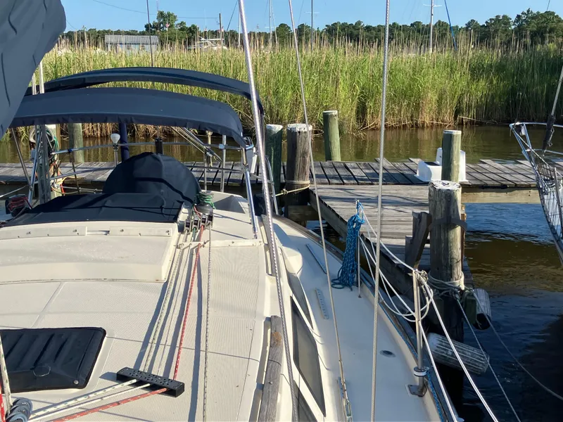 Slide: The Image of Sailboat S2 11.0A (1981) docked near reeds, with blue canopy and wooden pier. - 13