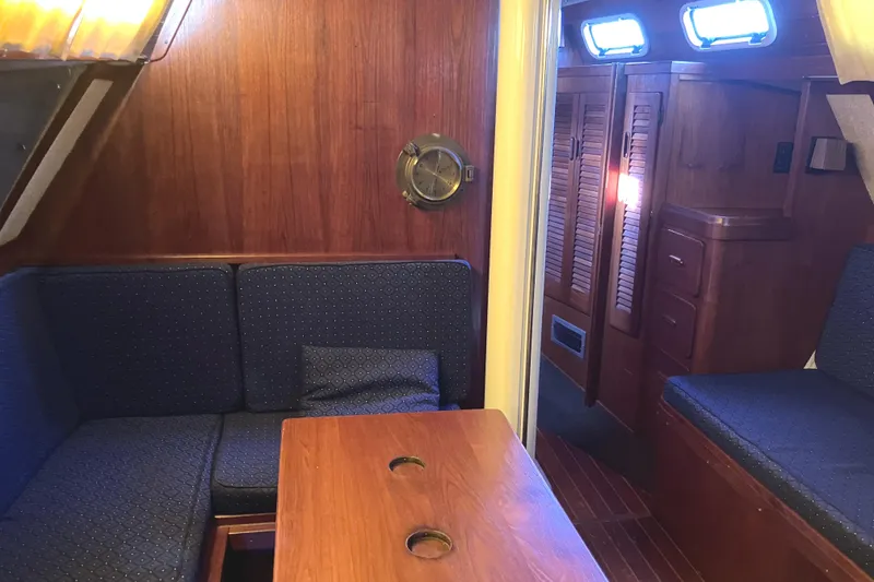 Slide: The Image of Interior of 1981 S2 11.0A sailboat with wooden paneling and blue cushioned seating. - 18