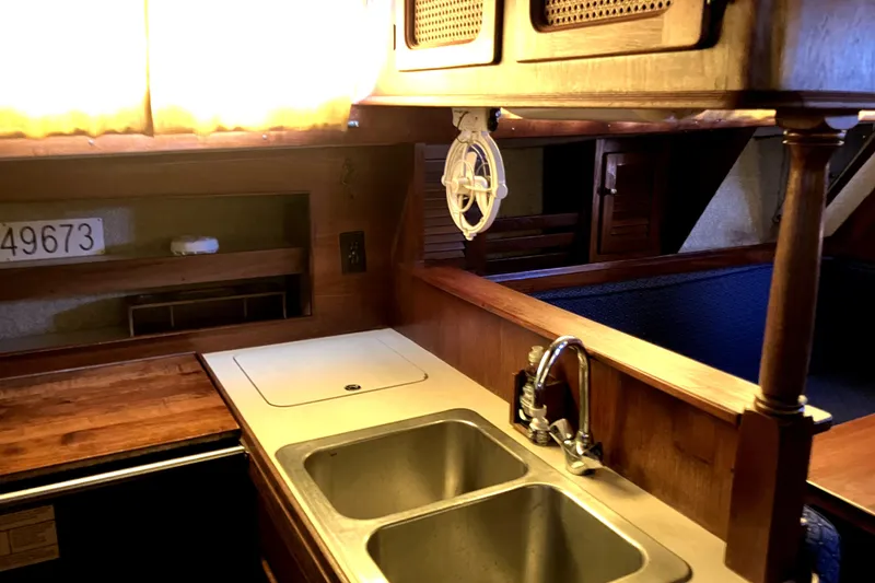 Slide: The Image of Interior of 1981 S2 11.0A sailboat kitchen with double sink and wooden cabinetry. - 19