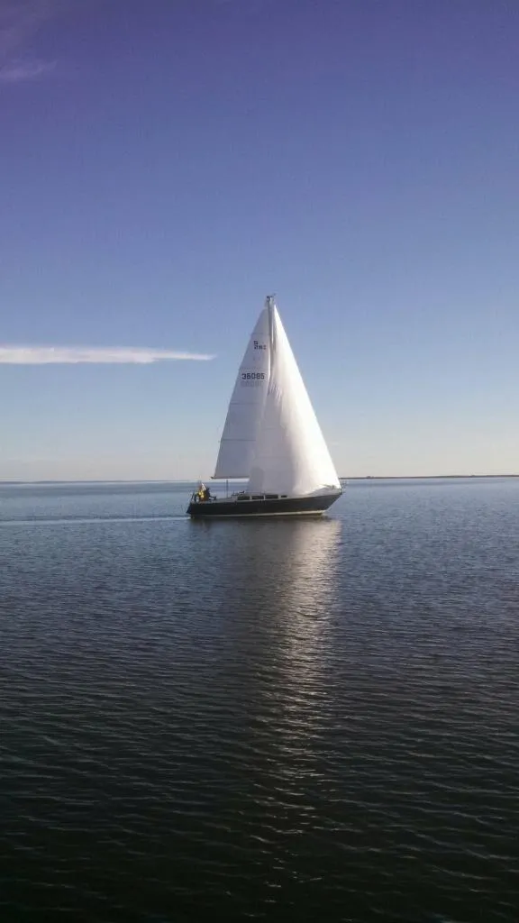 Slide: The Image of Sailboat S2 11.0A from 1981 gliding on calm waters under a clear blue sky. - 3