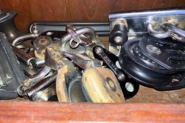Slide: The Image of Assorted sailing hardware in a wooden compartment, featuring pulleys and shackles from a 1981 S2 11.0A. - 35
