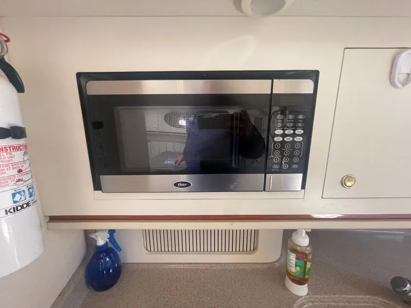 Slide: The Image of Microwave in 2001 Sea Ray 290 Amberjack boat kitchen, with fire extinguisher and cleaning supplies. - 14