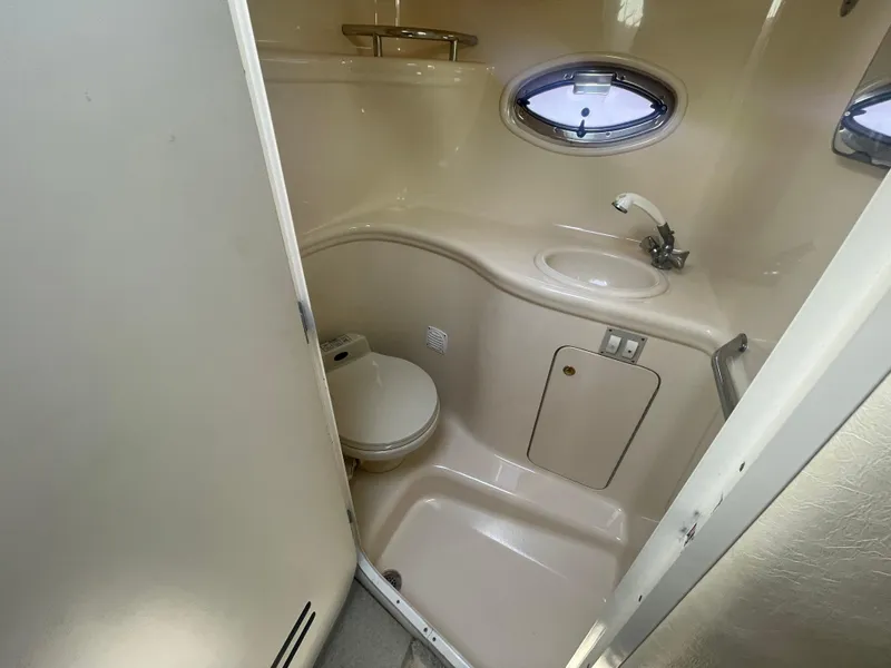 Slide: The Image of 2001 Sea Ray 290 Amberjack bathroom with toilet, sink, and porthole window. - 17