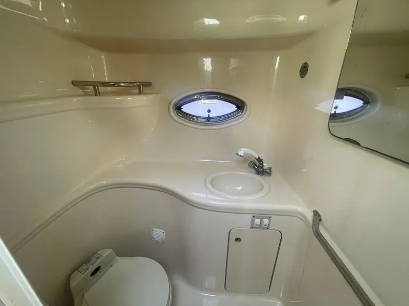 Slide: The Image of 2001 Sea Ray 290 Amberjack bathroom with sink, toilet, and porthole window. - 19