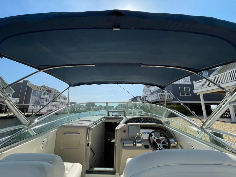 Slide: The Image of 2001 Sea Ray 290 Amberjack boat interior with canopy, docked near waterfront homes. - 24