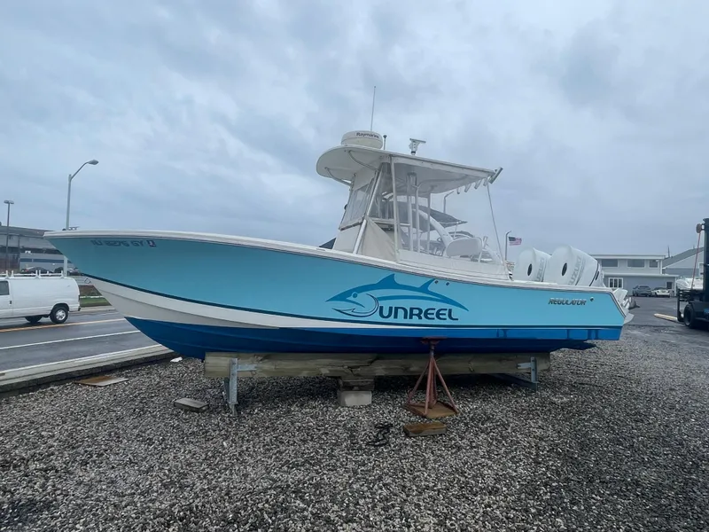 Slide: The Image of 2006 Regulator 24 FS boat on display, featuring a blue hull with "UNREEL" branding. - 12