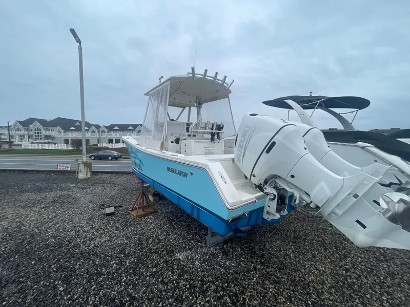 Slide: The Image of 2006 Regulator 24 FS boat on gravel, with buildings in the background, overcast sky. - 14