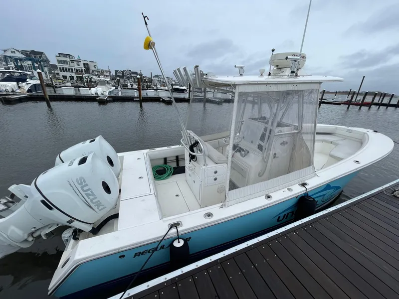 Slide: The Image of 2006 Regulator 24 FS boat docked with Suzuki outboard motor, marina background. - 2
