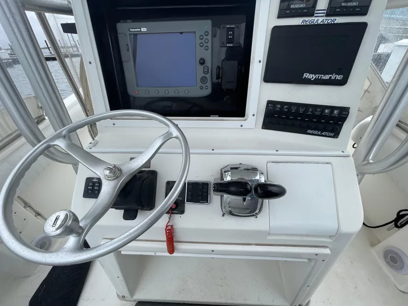 Slide: The Image of 2006 Regulator 24 FS boat dashboard with steering wheel and Raymarine navigation system. - 8