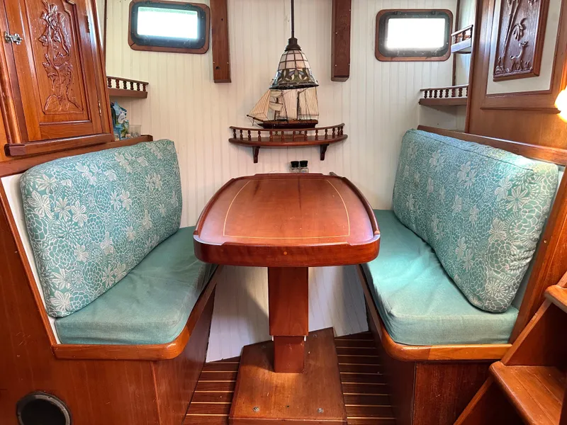 Slide: The Image of Cozy dining area in 1981 Island Trader 46 sailboat with wooden table and cushioned seating. - 11