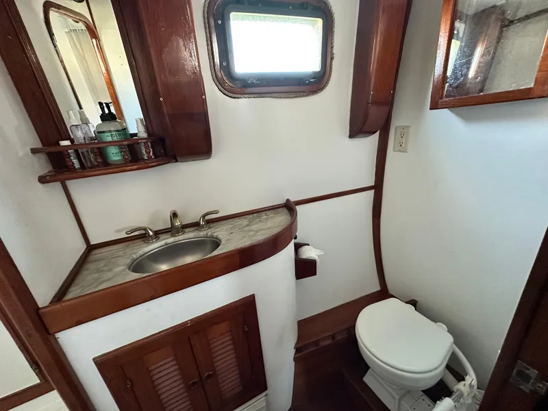 Slide: The Image of 1981 Island Trader 46 yacht bathroom with sink, toilet, wooden cabinetry, and porthole window. - 23