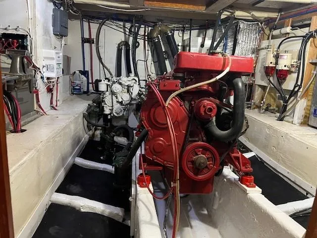 Slide: The Image of Engine room of 1981 Island Trader 46 with red and white engines, wiring, and equipment. - 26