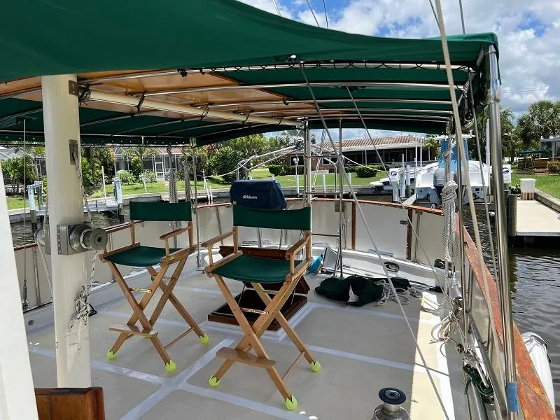 Slide: The Image of 1981 Island Trader 46 sailboat deck with green canopy and chairs, docked at marina. - 3