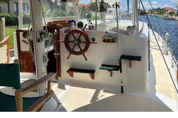 Slide: The Image of 1981 Island Trader 46 sailboat cockpit with wooden wheel and seating, docked by a canal. - 4