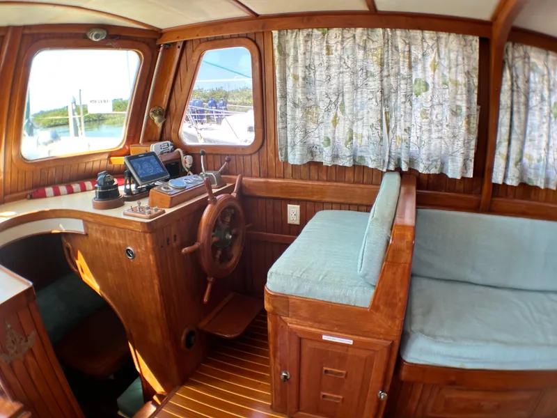 Slide: The Image of 1981 Island Trader 46 interior with wooden helm, nautical decor, and cushioned seating. - 7