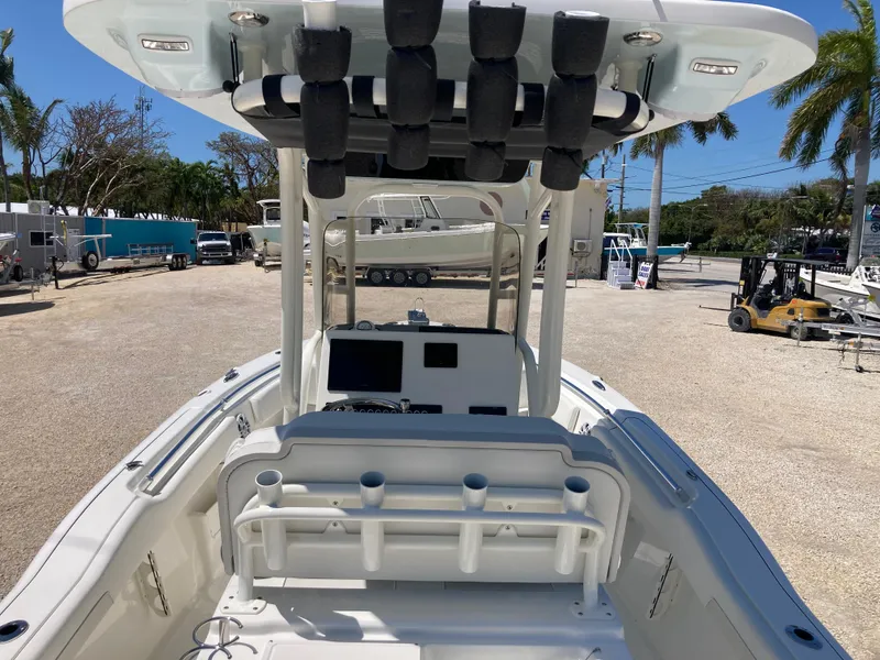 Slide: The Image of 2025 Key West 239FS boat interior with console and rod holders, parked outdoors. - 7