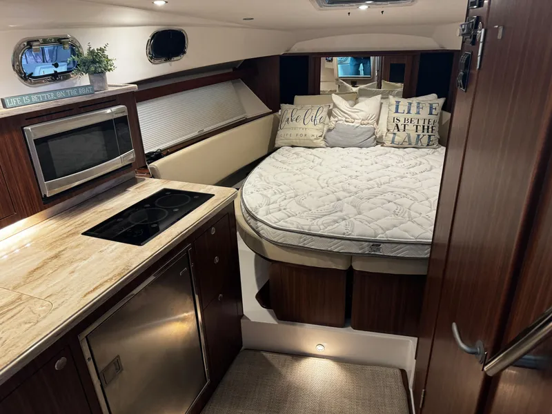 Slide: The Image of 2018 Pursuit OS 355 Offshore cabin with bed, kitchenette, and cozy decor. - 25