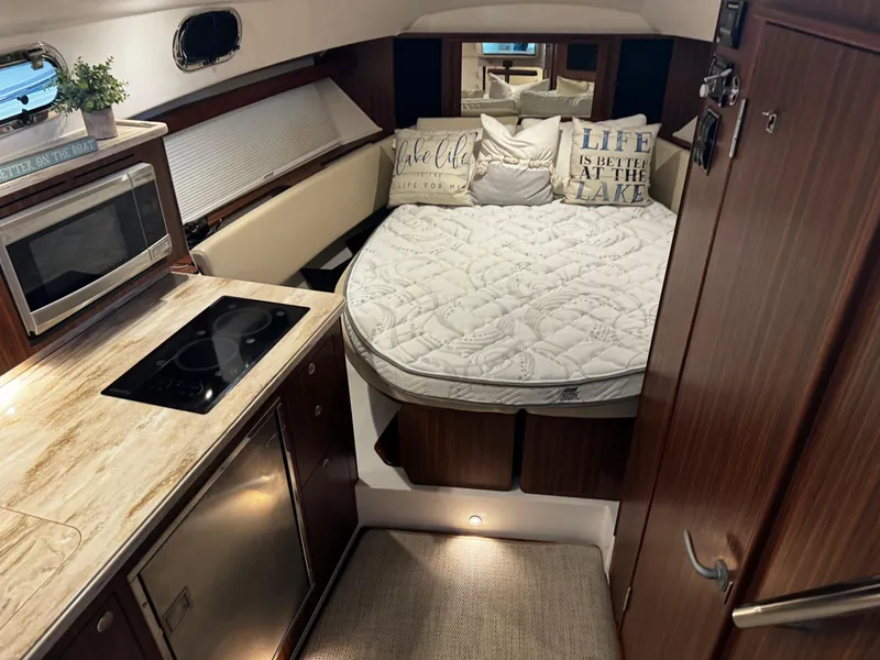 Slide: The Image of 2018 Pursuit OS 355 Offshore cabin with bed, kitchenette, and cozy decor. - 26