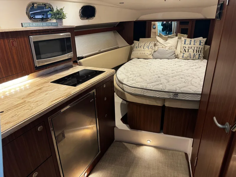 Slide: The Image of 2018 Pursuit OS 355 Offshore cabin with kitchenette, bed, and cozy decor. - 27