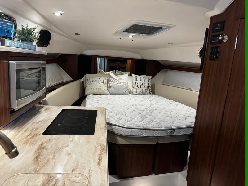 Slide: The Image of 2018 Pursuit OS 355 Offshore cabin with bed, kitchenette, and cozy decor. - 32