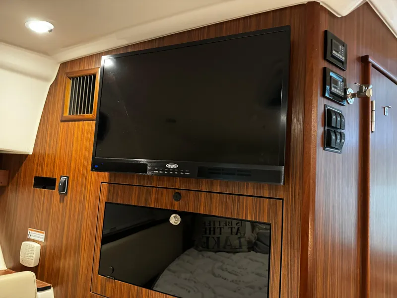 Slide: The Image of 2018 Pursuit OS 355 Offshore cabin with mounted TV and wood paneling. - 34