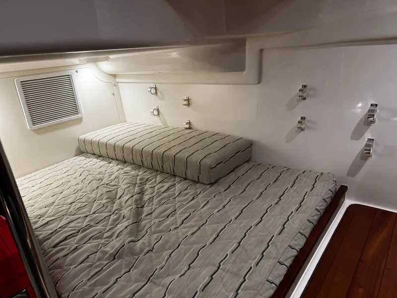 Slide: The Image of 2018 Pursuit OS 355 Offshore cabin interior with striped bedding and wooden flooring. - 38
